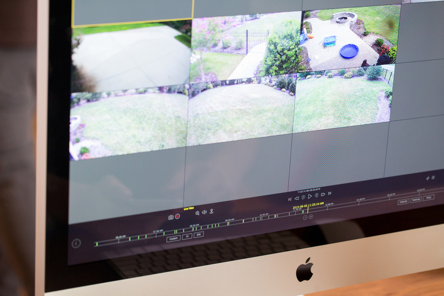 Desktop screen displaying live home surveillance footage from various outdoor angles, including the yard and patio.